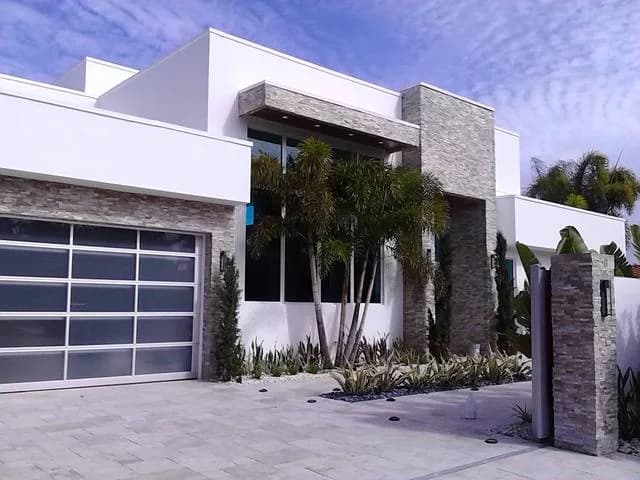 Modern home with glass garage door and stone facade