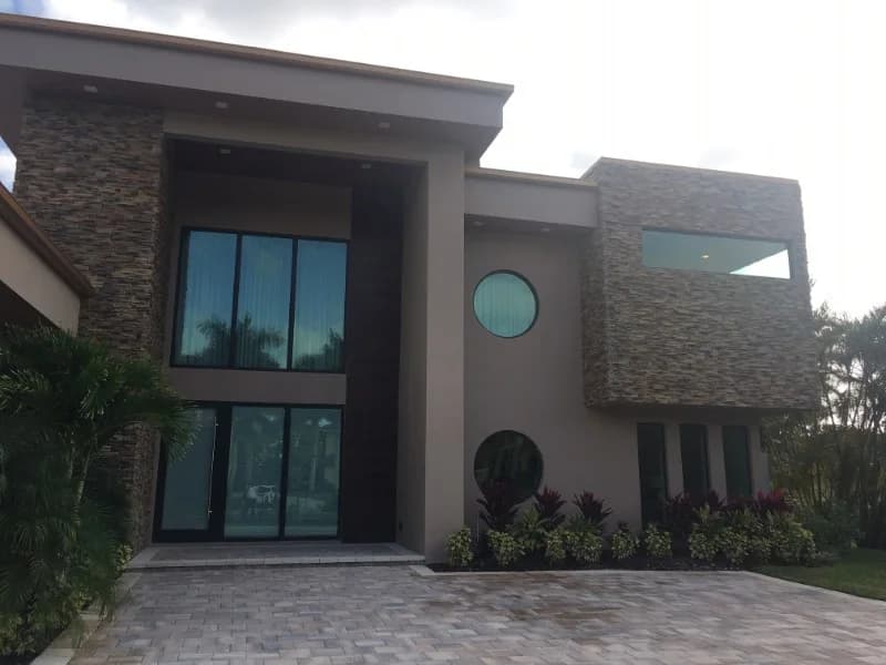 Modern stone and stucco facade with dark impact windows