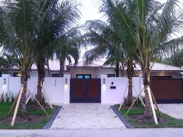 Palm-lined driveway to a modern entry with impact doors